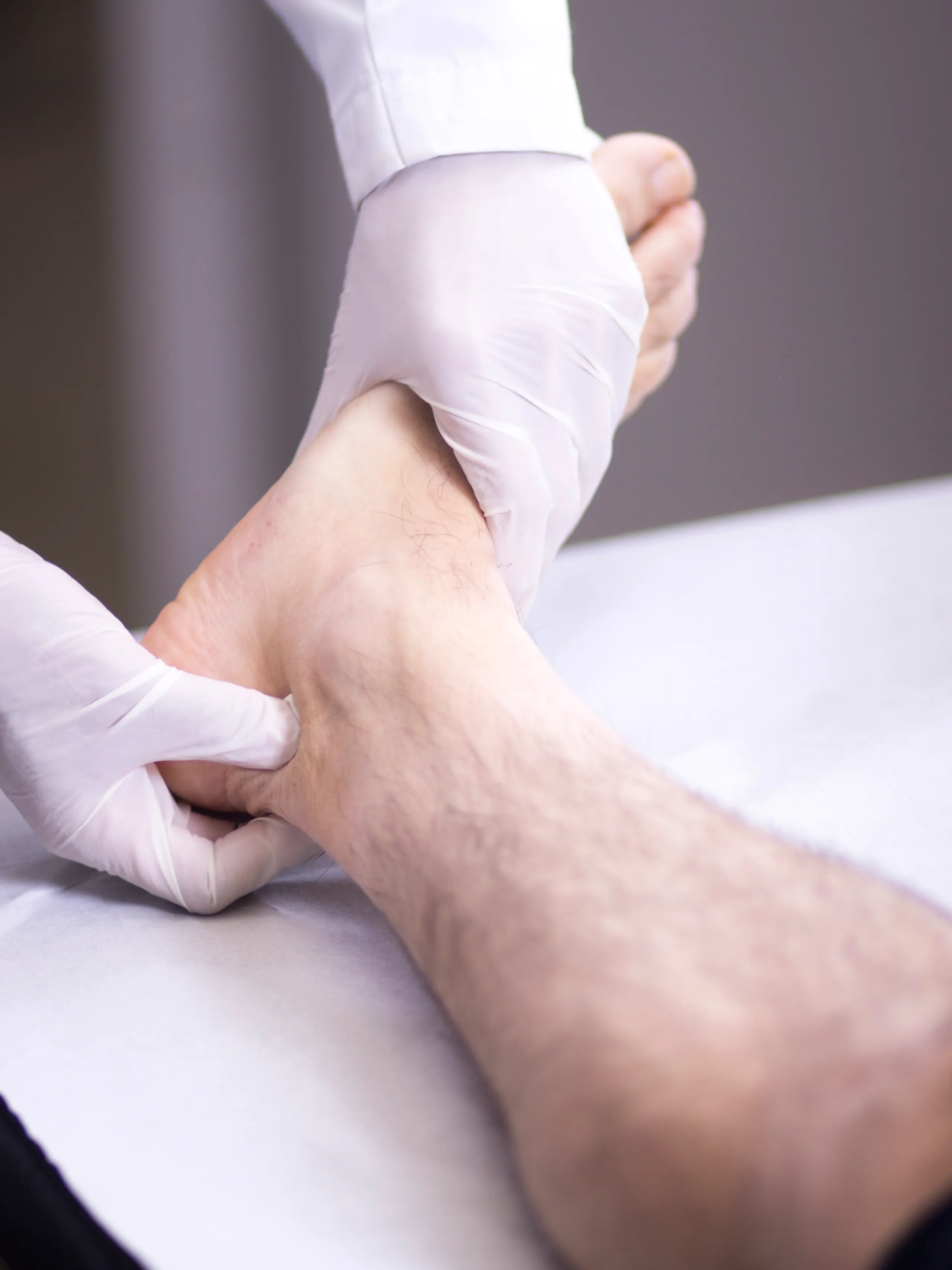 Médico examinando pulso do pé para avaliar obstrução arterial nas pernas